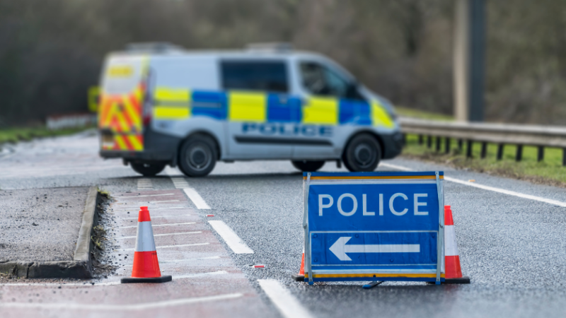 Police van parked road behind cones and police signs