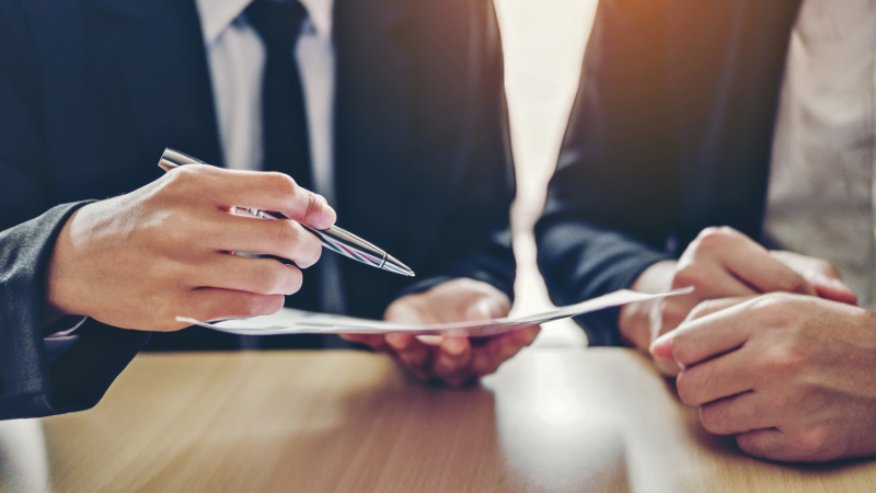 Close up of hands of two people in suits reviewing a document
